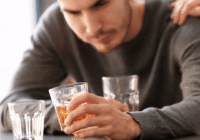 A lonely person sitting with alcohol, symbolizing emotional struggles and addiction